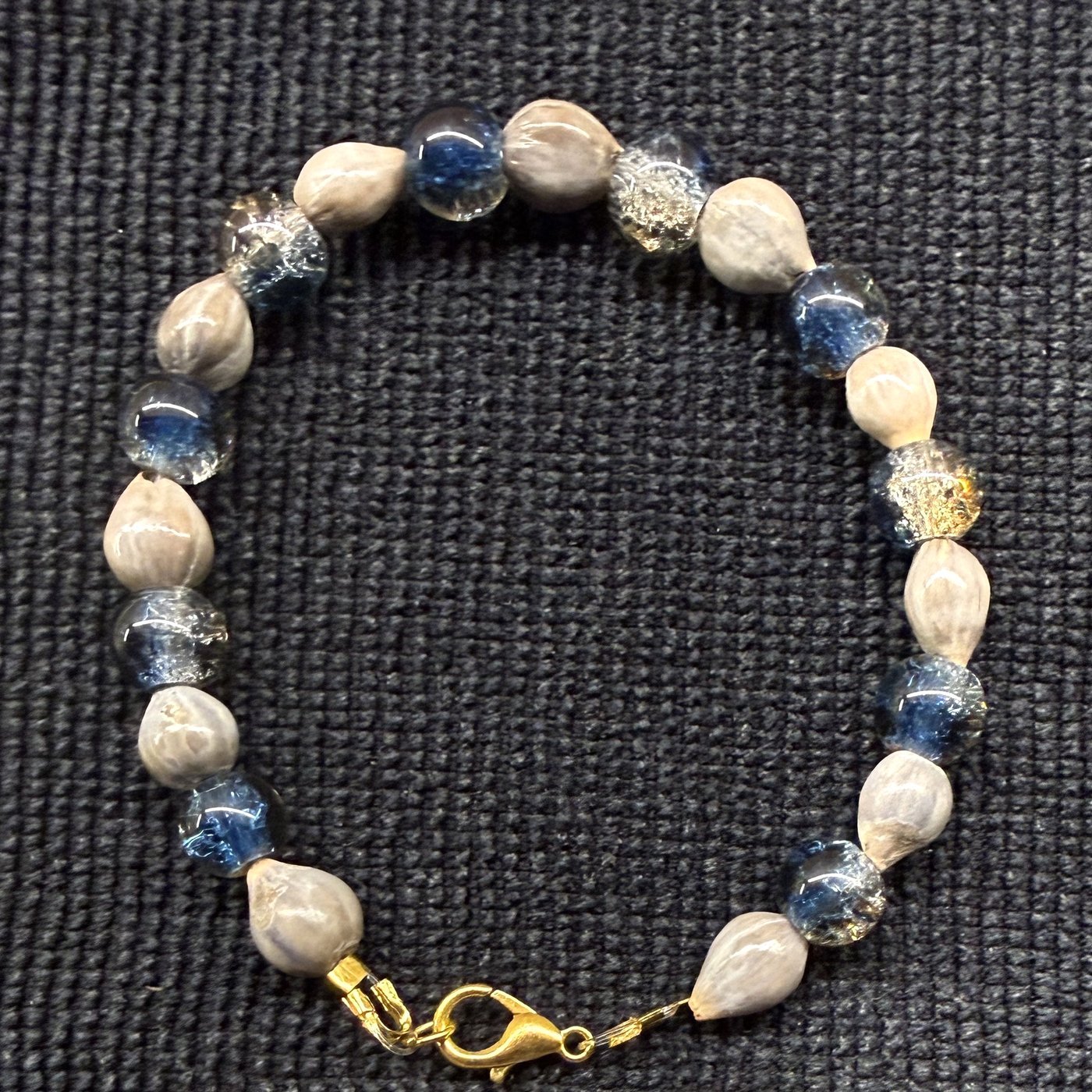 Bracelet 12, Blue Meadow, 7.5": navy blue, clear and gold-flecked crackle glass beads alternating with grey Job's tears seeds and a gold clasp.